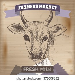 Vintage farmers market label with milk cow. Placed on wooden texture. Includes hand drawn elements. 