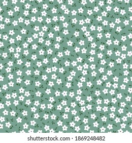 Vintage floral background. Seamless vector pattern for design and fashion prints. Elegant floral pattern with small white flowers on a green background. Ditsy style.