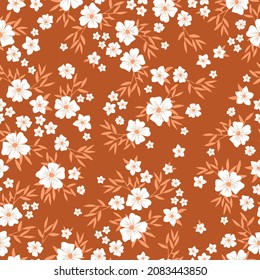 Vintage floral background. Seamless vector pattern for design and fashion prints. Floral pattern with white flowers and orange leaves on a terracotta background.