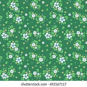 Vintage floral background. Seamless vector pattern for design and fashion prints. Flowers pattern with small white flowers on a green background. Ditsy style. 