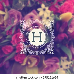 Vintage Monogram Logo Template With Flourishes Elegant Ornament Elements On A Blurred Flowers Background. Design With Letter For Cafe, Shop, Store, Restaurant, Boutique, Hotel, Fashion And Etc.