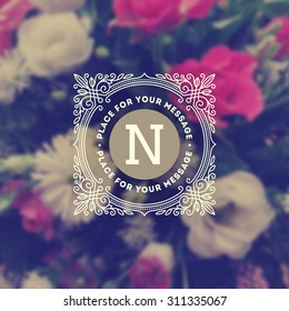 Vintage monogram logo template with flourishes calligraphic elegant ornament elements on a blurred flowers background. Identity design with letter for cafe, shop, store, restaurant, boutique, and etc
