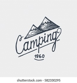 vintage old logo or badge, label engraved and old hand drawn style with lettering camping and mountains.