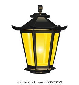 Vintage street light of dark metal, glowing with yellow light, on a white background