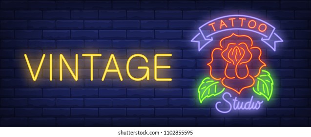 Vintage tattoo studio neon sign. Red rose on bright inscription on dark brick wall. Vector illustration in neon style for tattoo salon or signboard