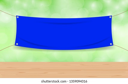 vinyl fabric blue on green bokeh background and wood plank table, mock up textile fabric empty for banner advertising stand hanging, indoor outdoor fabric vinyl backdrop for copy space presentation ad