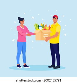 Volunteer holding a donation box, package with grocery. Humanitarian workers handing out food to people in need.Charity, food donation for needy and poor, homeless people