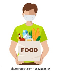 Volunteer in a medical mask with a food package. Young man wearing a medical mask to prevent the spread of the corona virus. Person holds grocery products in a bag.