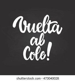 Vuelta al cole - Back to school, lettering calligraphy phrase in Spanish, handwritten text isolated on the black chalkboard background. Fun calligraphy for greeting and invitation card.