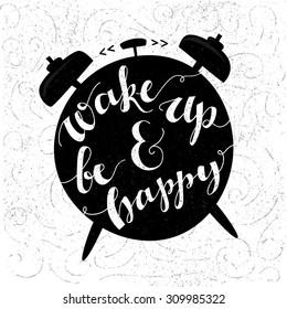 Wake up and be happy. Positive inspirational quote handwritten with modern calligraphy style at black alarm clock shape. Typography vector art for cards, posters and social media content.