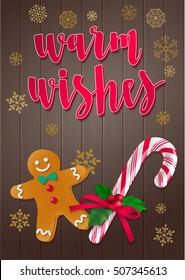 Warm Wishes.  Holiday greeting card with calligraphy and decorative elements. Handwritten modern lettering with candy cane, holly and gingerbread man on dark wooden background.