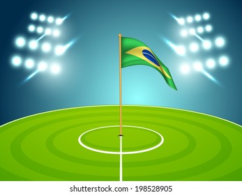 Waving Brazil Flag on shiny green football stadium in night background
