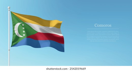 Waving flag of Comoros on a pole with a blue sky backdrop with copyspace