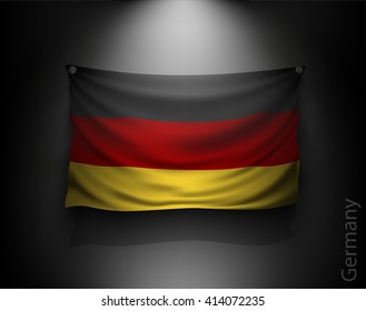 waving flag germany on a dark wall with a spotlight, illuminated