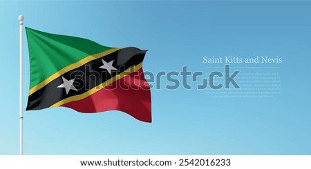 Waving flag of Saint Kitts and Nevis on a pole with a blue sky backdrop with copyspace