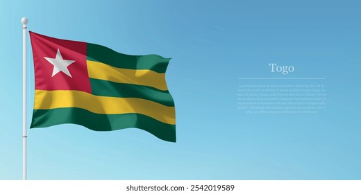 Waving flag of Togo on a pole with a blue sky backdrop with copyspace