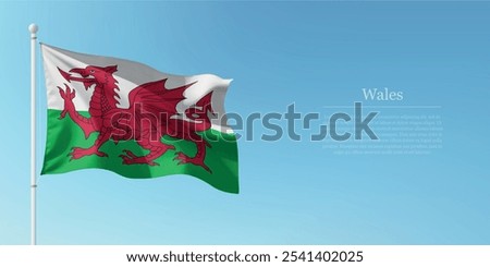 Waving flag of Wales on a pole with a blue sky backdrop with copyspace