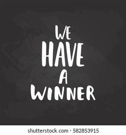 We have a winner - hand drawn lettering phrase for film festival award isolated on the black chalkboard background. Fun brush ink inscription for photo overlays, card or t-shirt print, poster design