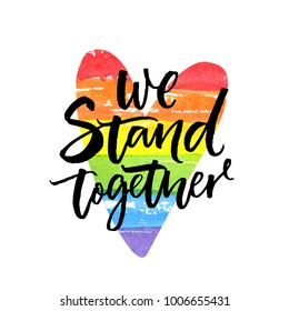 We stand together. Inspirational LGBT slogan han dwritten on rainbow flag heart