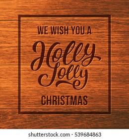 We wish you a Holly Jolly Christmas typographic text on wooden background. Vintage vector greeting card design with hand lettering for Xmas and winter holidays