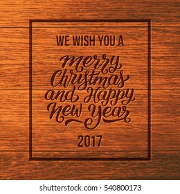 We wish you a Merry Christmas and Happy New Year 2017 typographic text on wooden background. Vintage vector greeting card design with hand lettering for winter holidays