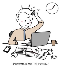 Weary young man working overtime at desk. Unhappy businessman sitting at desk, concentrating on work. Busy and frustrated man working hard at desk cluttered with crumpled paper balls and sheets.