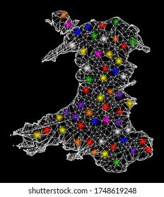 Web mesh vector map of Wales with glitter effect on a black background. Abstract lines, light spots and circle dots form map of Wales constellation.