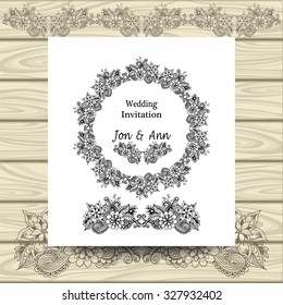 Wedding invitation with doodle floral elements on white on wood background
