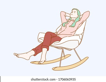 Weekends finally! Relaxed brunette girl is sitting on modern chair in light cozy room at home. She is enjoying peace and morning. 