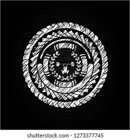 weightlifting inside of crown icon inside chalkboard emblem written on a blackboard