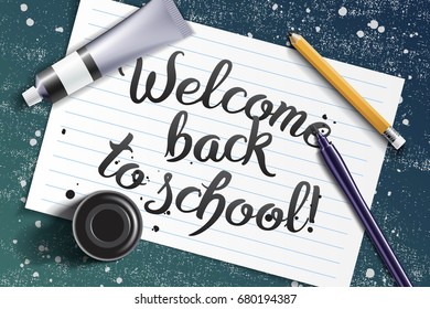 Welcome Back to School hand drawn lettering with calligraphy mock-up with brush pen, sharp pencil, paint tube and black ink bottle on the background of white sheet of paper and grunge chalk board