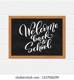 Welcome back to school hand-drawn lettering background. Realistic blackboard with autumn leaves. Vector illustration