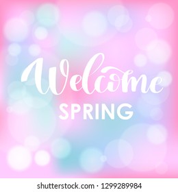 Welcome Spring. Hand drawn calligraphy and brush pen lettering on light blue and fresh pink blured background with bokeh. Design for holiday greeting card, invitation, posters, sale, banners