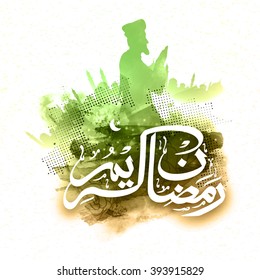 White Arabic Islamic Calligraphy of text Ramadan Kareem with illustration of praying man on mosque silhouetted abstract background.