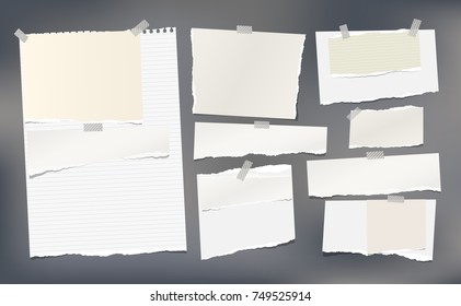 White, beige ripped horizontal paper strips, notebook, note paper for text or message stuck with sticky tape on dark gray background.