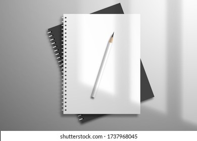 White and black spiral notebooks and pencil is on top. Mockup for design with light from a window