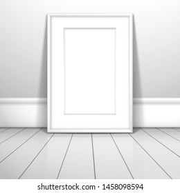 A white blank frame with passe-partout for a picture or poster stands near the wall on the boards. Mockup for gallery design with shadow