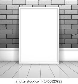 A white blank frame for a picture or poster stands near the brick wall on the boards. Mockup for gallery design with shadow