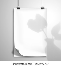 A white blank notebook or an album with a bent top sheet hang on the clips. The shadow of the flower with leaves in a ceramic vase is on top.  Mockup with element for design