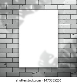 White blank rectangle or sheet of paper hanging on a brick wall. The shadow of the Monstera plant is on top. Mockup for design