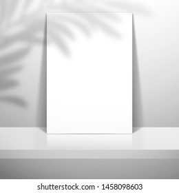 A white blank sheet of paper or card stands near the wall on the shelf. The shadow of the leaves of the palm tree is on top. Mockup for design