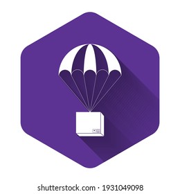 White Box flying on parachute icon isolated with long shadow. Parcel with parachute for shipping. Delivery service, air shipping concept, bonus concept. Purple hexagon button. Vector Illustration