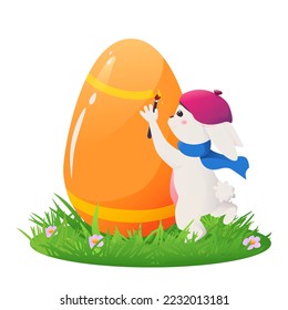 Un lapin blanc en forme d'artiste peint un oeuf de Pâques sur l'herbe avec une brosse.