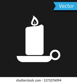 White Burning candle in candlestick icon isolated on black background. Old fashioned lit candle. Cylindrical aromatic candle stick with burning flame. Vector Illustration