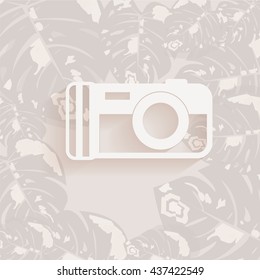 white camera in gray tropical leaves backdrop