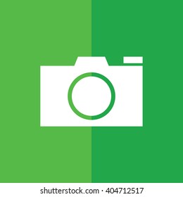 White camera vector icon. Green background