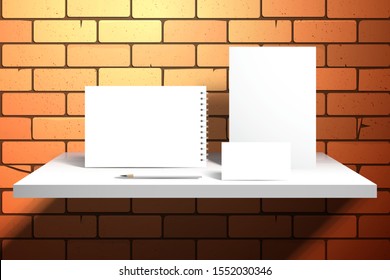 White card, notepad or diary, spiral notebook or album and pencil. Set of objects for design on a shelf near a brick wall