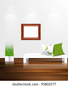 White couch with pillows against white wall with empty wooden frame.