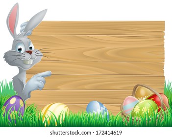 White Easter rabbit bunny peeking round a sign and pointing, chocolate Easter eggs and basket in front 