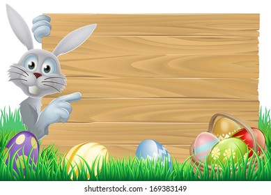 White Easter rabbit bunny pointing at a sign, with chocolate Easter eggs and basket